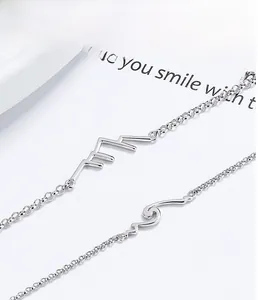 Macro detail of 925 sterling silver bracelets showing mountain and wave contour charms