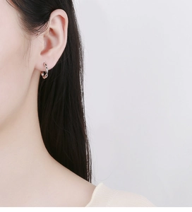 Close-up of minimalist S925 silver twisted hoop earrings worn by a model in soft light