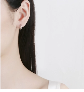 Détail d'une boucle d'oreille en argent 925 en forme d'étoile portée par un mannequin