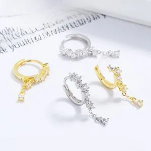 Macro shot of 925 sterling silver D-shaped earrings with zircon square charms in gold and silver