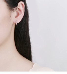 Detailed close-up of a twisted silver hoop earring with sparkling micro-pave crystals