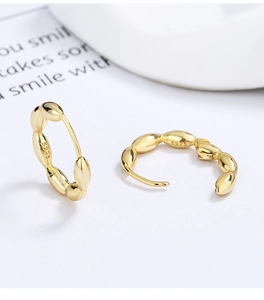 Detailed close-up of S925 sterling silver stamp on polished gold hoop earrings