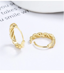 Macro view of gold S925 sterling silver twist hoop earrings with pavé diamond details