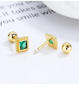 Macro shot of 925 sterling silver gold square stud earrings with emerald green gemstones