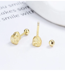 Macro detail of S925 engraved silver stud earrings with golden mineral texture