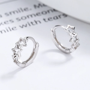 Boucles d'oreilles créoles en argent 925 avec étoiles évidées sur fond blanc épuré