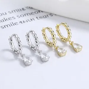 Détail macro de boucles d'oreilles goutte en zircone cubique, finitions argent et or