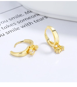 Gros plan du poinçon S925 et du pendentif en zircon sur une boucle d'oreille dorée