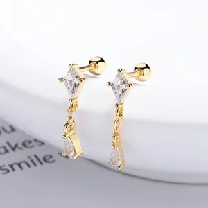 Macro shot of gold geometric earrings with teardrop zircon and screw-back closure