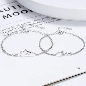 925 silver couples bracelets with mountain and wave pendants on magazine background
