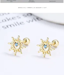 Close-up of gold 925 silver sun stud earrings with a blue gem and screw ball backing