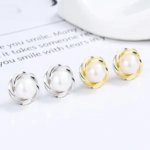 Detail of twisted metal petal pearl stud earrings in gold and silver finishes