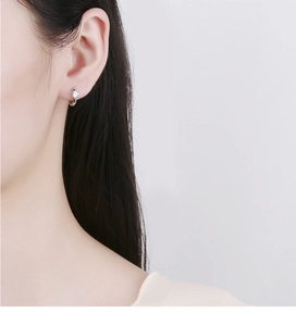 Close-up of minimalist 925 sterling silver hoop earring with sparkling zircon on model