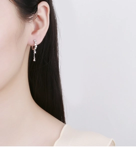 Macro detail of 925 silver ear cuff with tassel chain and zircons on female ear