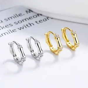 Detail of silver and gold bamboo-shaped hoop earrings with sparkling micro-inlaid stones