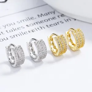 Detail of silver and gold huggie earrings featuring triple row micro-pave cubic zirconia