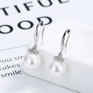 Macro shot of 925 silver pearl drop earrings with sparkling zircon accents on white box