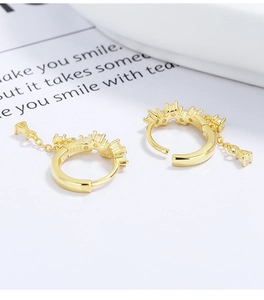 Detailed macro of gold S925 silver hoop earrings featuring zircons and triangle drop fringe