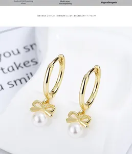 Detail of 925 sterling silver gold bow earrings with white pearls and plating texture