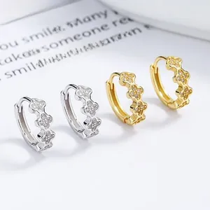 Detailed view of silver and gold clover earrings with sparkling cubic zirconia stones