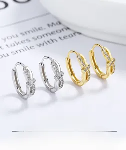 Detailed view of silver and gold bow-shaped earrings set with sparkling crystals