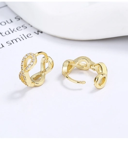 Macro view of gold-plated silver infinity earrings featuring S925 hallmark and cubic zirconia