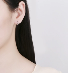 Détail d'une boucle d'oreille feuille en argent 925 portée montrant une texture fine