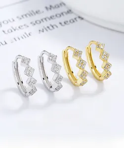 Macro shot of 925 silver geometric hoop earrings with sparkling zircon inlay in gold and silver