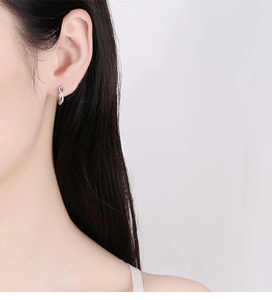 Close-up of model wearing twisted S925 silver hoop earrings with pavé set cubic zirconia