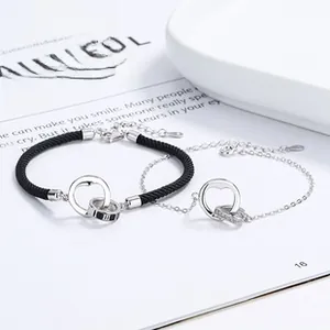 Close-up of 925 silver couple bracelets with double interlocking rings and woven cord detail