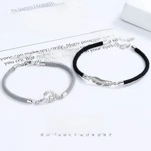 Detail view of 925 silver feather and crown charms on couple bracelets with woven ropes