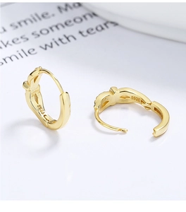 Detail of 925 silver golden bow hoop earrings with S925 hallmark on polished surface