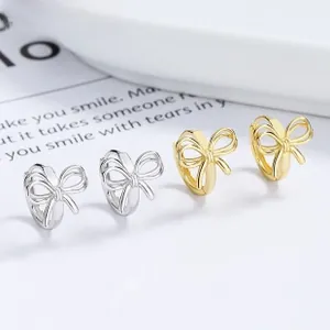 Vue macro détaillée de boucles d'oreilles nœud en argent 925 et or sur un plateau minimaliste