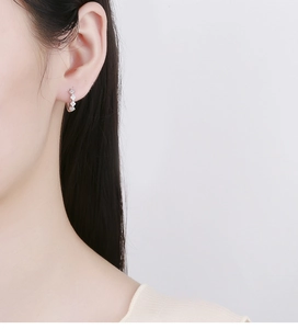 Close-up of sparkling cubic zirconia paved hoop earrings worn on a model's ear lobe