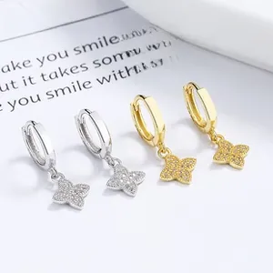 Macro shot of silver and gold four-leaf clover earrings with sparkling pavé zircons