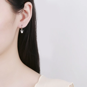 925 silver bow earrings with round white pearl on model against light gray background