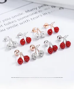 Détail des boucles d'oreilles cerise en argent, or et or rose serties de cristaux brillants