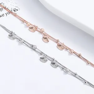 Gros plan de bracelets double couche en argent et or rose avec pendentifs feuille de ginkgo