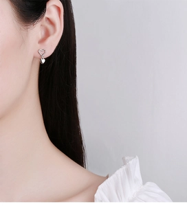 Close-up of a 925 sterling silver heart-shaped drop earring on an Asian female model