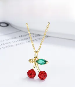 Macro shot of 925 sterling silver cherry pendant with red crystals and green leaf
