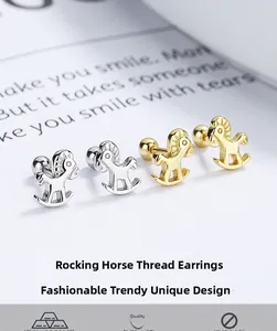 Détails macro de boucles d'oreilles cheval à bascule dorées et argentées sur un livre