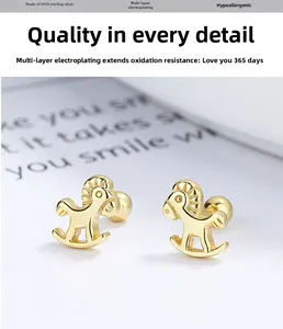 Vue macro de boucles d'oreilles cheval à bascule en argent 925 doré sur blanc
