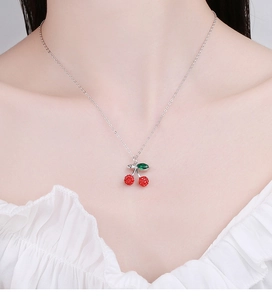 Close-up of red cherry pendant necklace with crystal stones on elegant silver chain