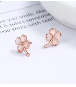Macro view of four-leaf clover studs with pink cat-eye stone and rose gold finish