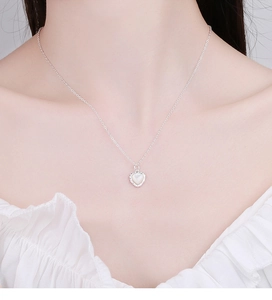Détail du collier cœur en argent 925 avec nacre blanche porté par un mannequin élégant