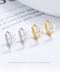 Détail de boucles d'oreilles fleur avec cristaux clairs en finitions or et argent