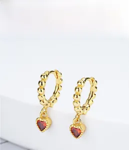 Close-up of gold S925 silver hoop earrings with vibrant red heart-shaped gemstone charms