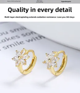 Détail de boucles d'oreilles fleur dorées avec zircons et base en argent S925