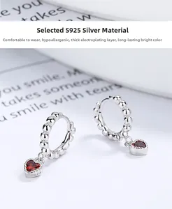 Detail of S925 silver hoop earrings with heart-shaped red gemstone and S925 hallmark