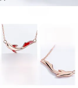 Macro detail of rose gold koi fish pendant with red enamel and diamond accents